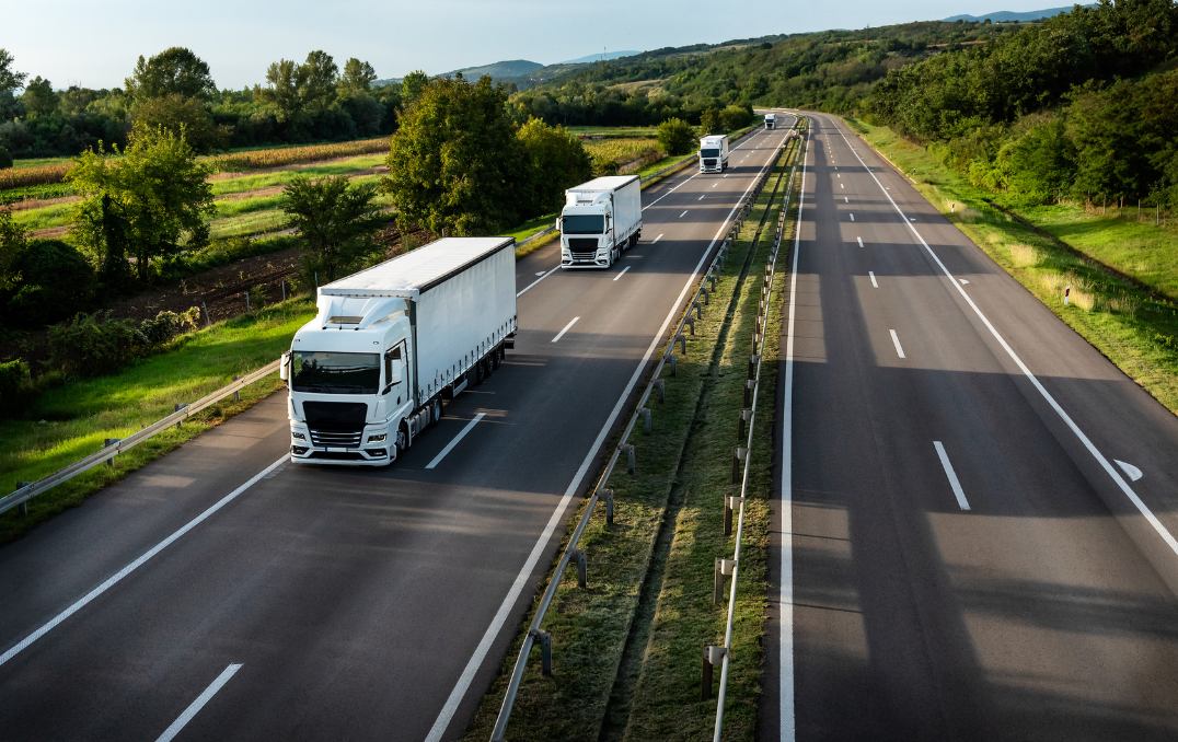 Trucks on a highway through green countryside